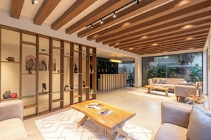 Decoração moderna com teto de madeira, balcão de recepção, sofá e mesa de centro.