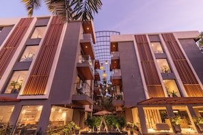 Um hotel moderno com um átrio central, várias varandas e uma área de estar ao ar livre bem iluminada.