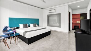 A modern hotel room with a large bed, a ceiling fan, a TV, and a desk with a chair. - Sibaya Courtyard By Stone Wood Premium  (Baga)