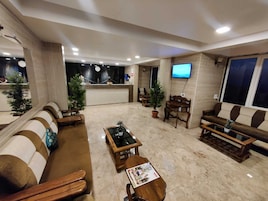 A hotel lobby with a reception desk, seating area, and a television.
