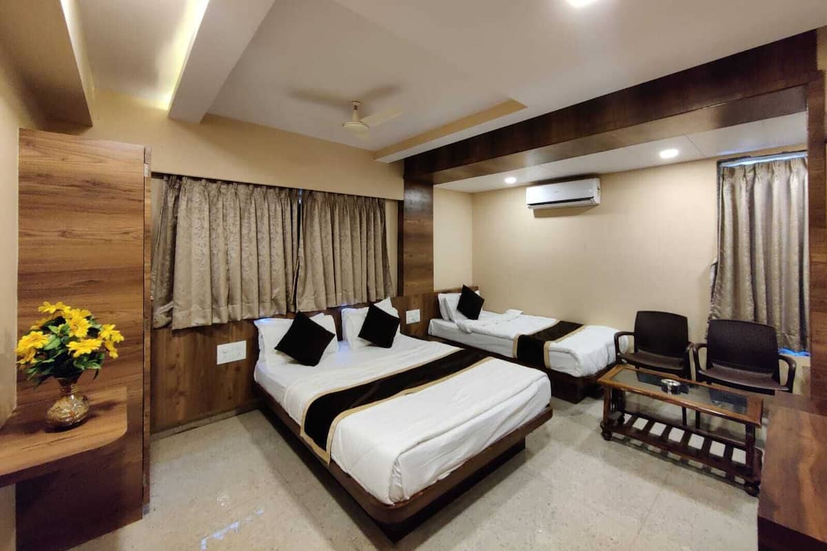 A hotel room with two beds, a desk, a chair, a ceiling fan, and an air conditioning unit.