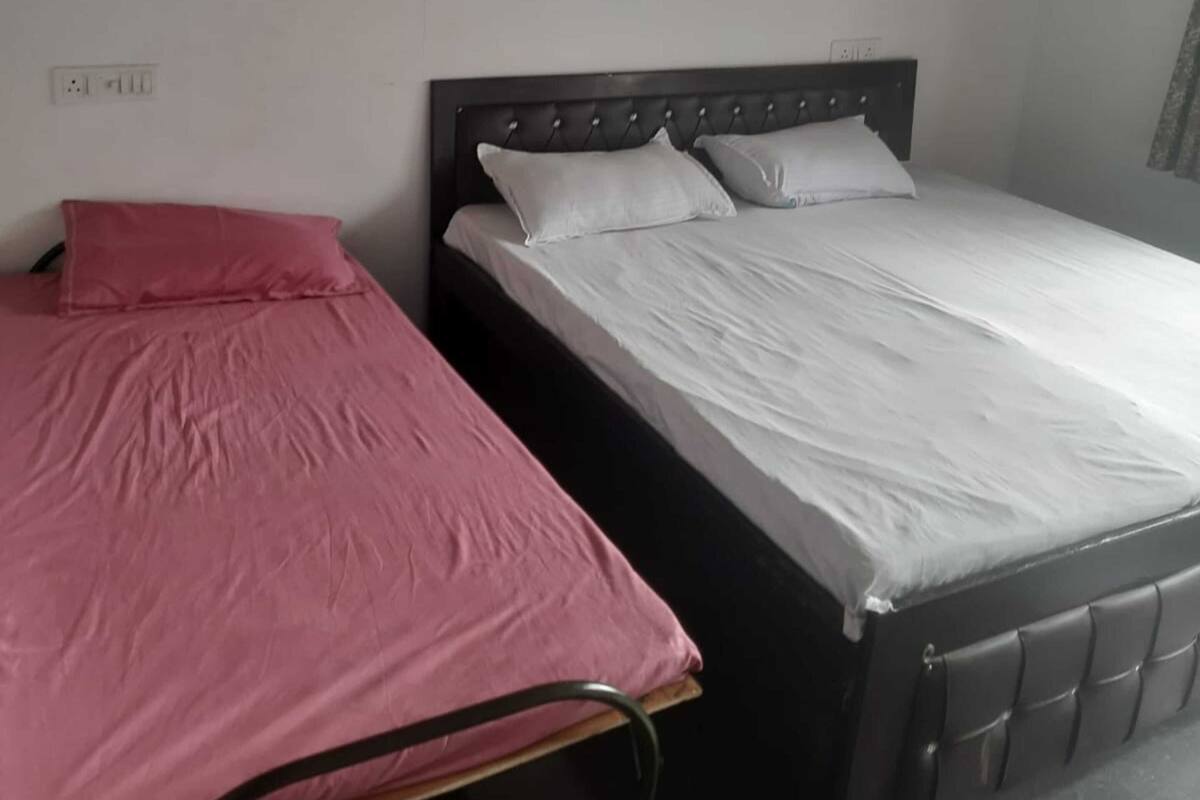 A single bed with a headboard, a bedside table, and a wall socket.