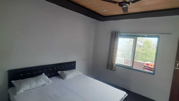 Un dormitorio con cama, ventilador de techo, ventana y vistas al exterior.