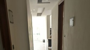 En hall med ett glänsande kaklat golv, en dörr på vänster sida och en lampa i taket.