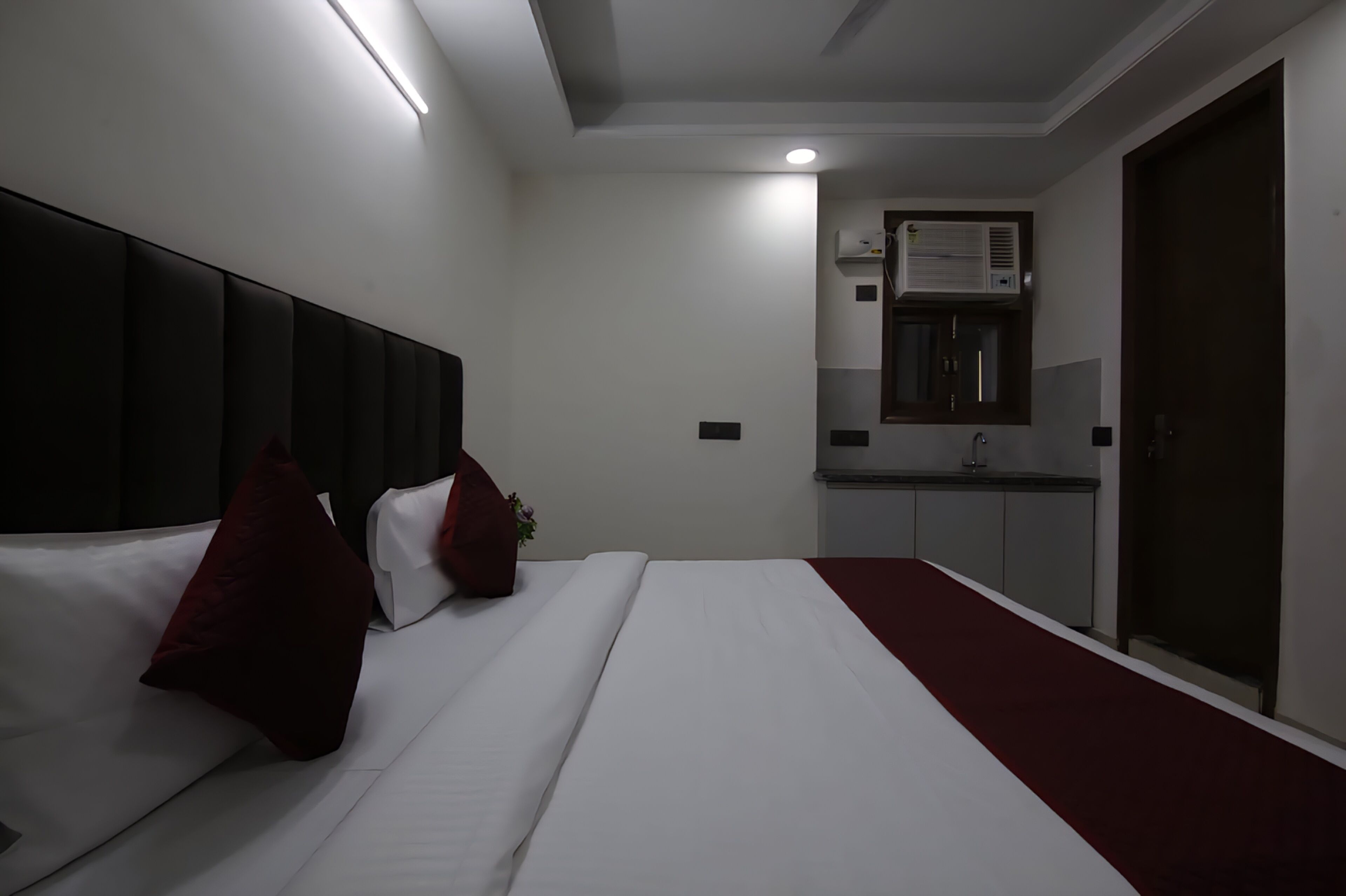 Una habitación de hotel con cama, alfombra roja, kitchenette y armario.