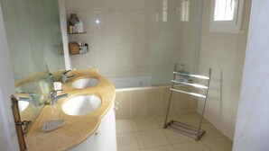 A bathroom with two sinks, a bathtub, a glass shower enclosure, and a towel rack.