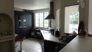 A kitchen with a built-in oven, a coffee maker, and a window with a view of greenery.