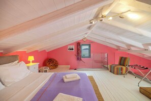 Ein Schlafzimmer im Dachgeschoss mit einem Bett, einem Sessel, einer Lampe und einem Fenster.