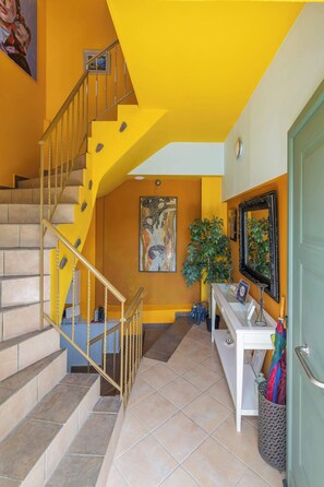 Un escalier recouvert de carreaux beiges, un bureau blanc avec un miroir et une porte verte.
