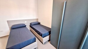 A small, modern room with two single beds, a wardrobe, and a tiled floor. - Air-conditioned apartment with sea view terrace - Santa Maria Castellabate (Castellabate)