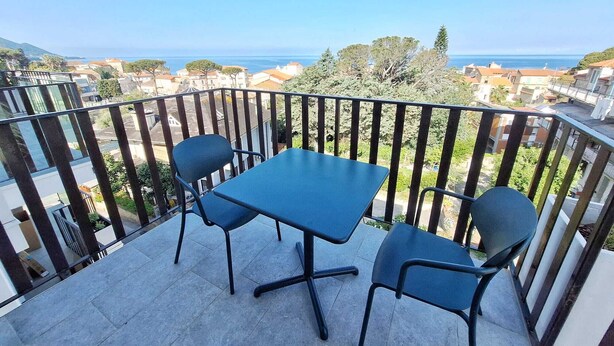 A balcony with a table and chairs, overlooking a coastal town and the sea. - Air-conditioned apartment with sea view terrace - Santa Maria Castellabate (Castellabate)