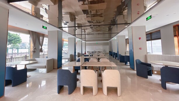 Un restaurante espacioso con techos altos, mobiliario moderno y amplias ventanas.