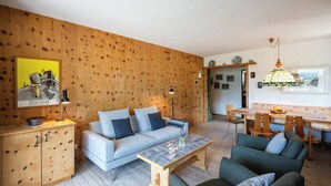 Un salon comprenant un canapé, des fauteuils, une table basse et un coin repas avec une table et des chaises.