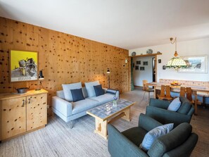 Ein Wohnzimmer mit einer Couch, Sesseln, einem Couchtisch und einem Essbereich mit Tisch und Stühlen.