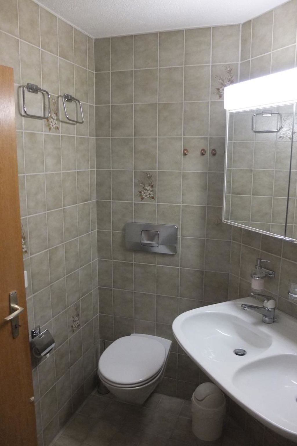 A small bathroom with a toilet, sink, and mirror.