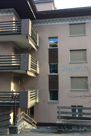 A building with a beige exterior, multiple balconies, and a sign that reads 'Bergblick.' - 2½-Zimmerwohnung by Interhome (Davos)