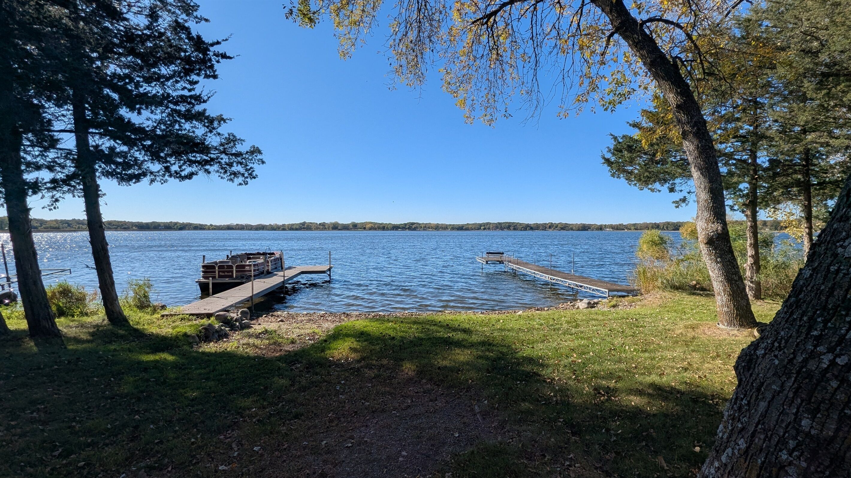 A dock extending into a calm lake, surrounded by trees.