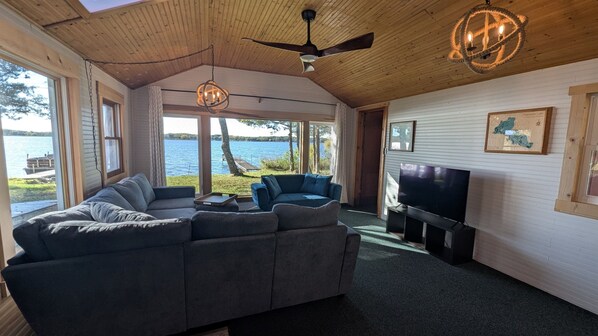 A modern living room with a sectional sofa, a television, and a view of a lake.