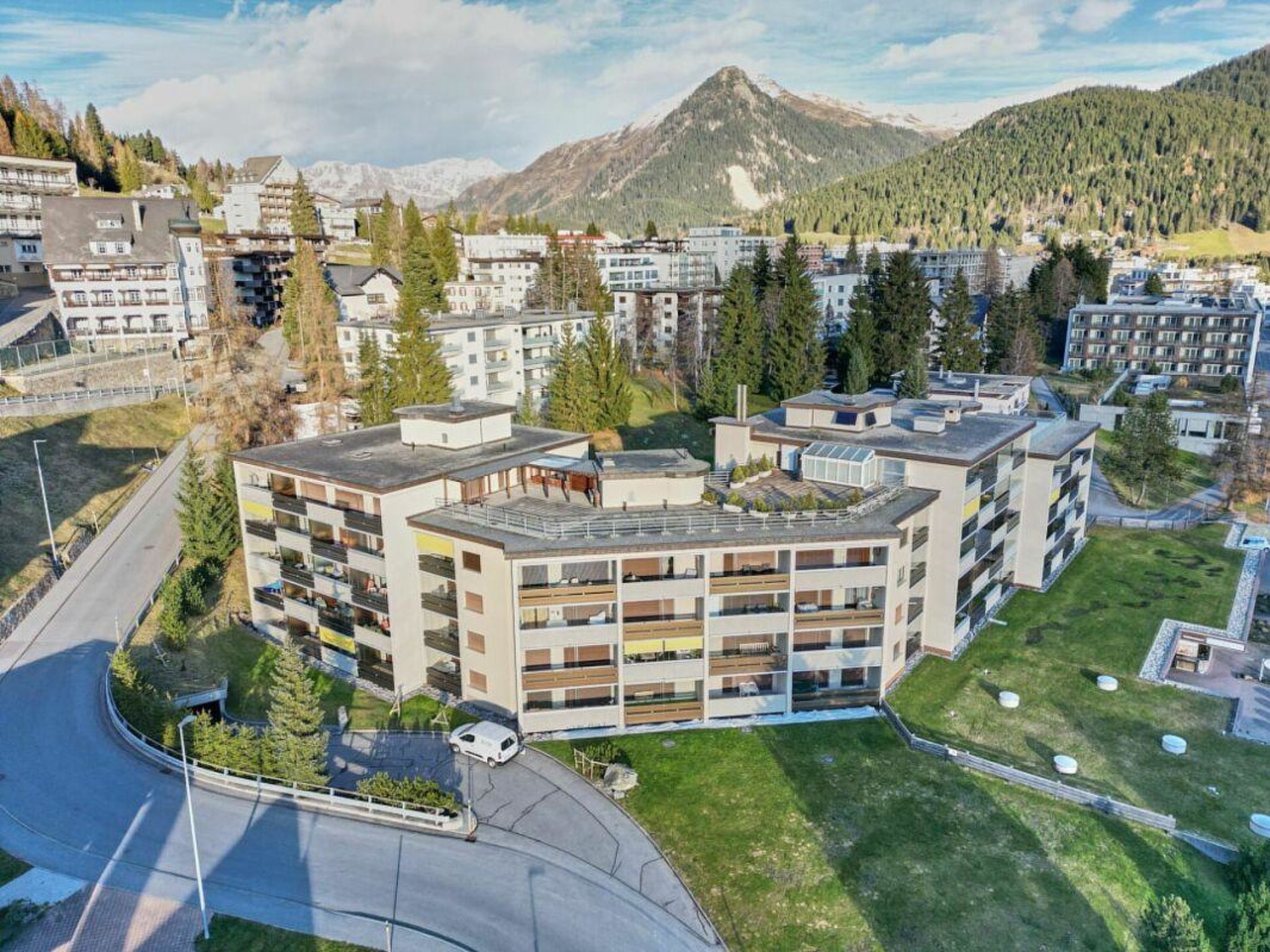 Un hôtel à plusieurs étages doté de balcons, entouré de verdure et de montagnes.