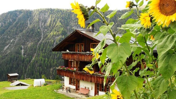 Eine Chalet mit Balkon, umgeben von einer Berglandschaft.