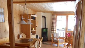 Ein Holzinnenraum mit Essbereich, Kamin und Blick durch ein Fenster.