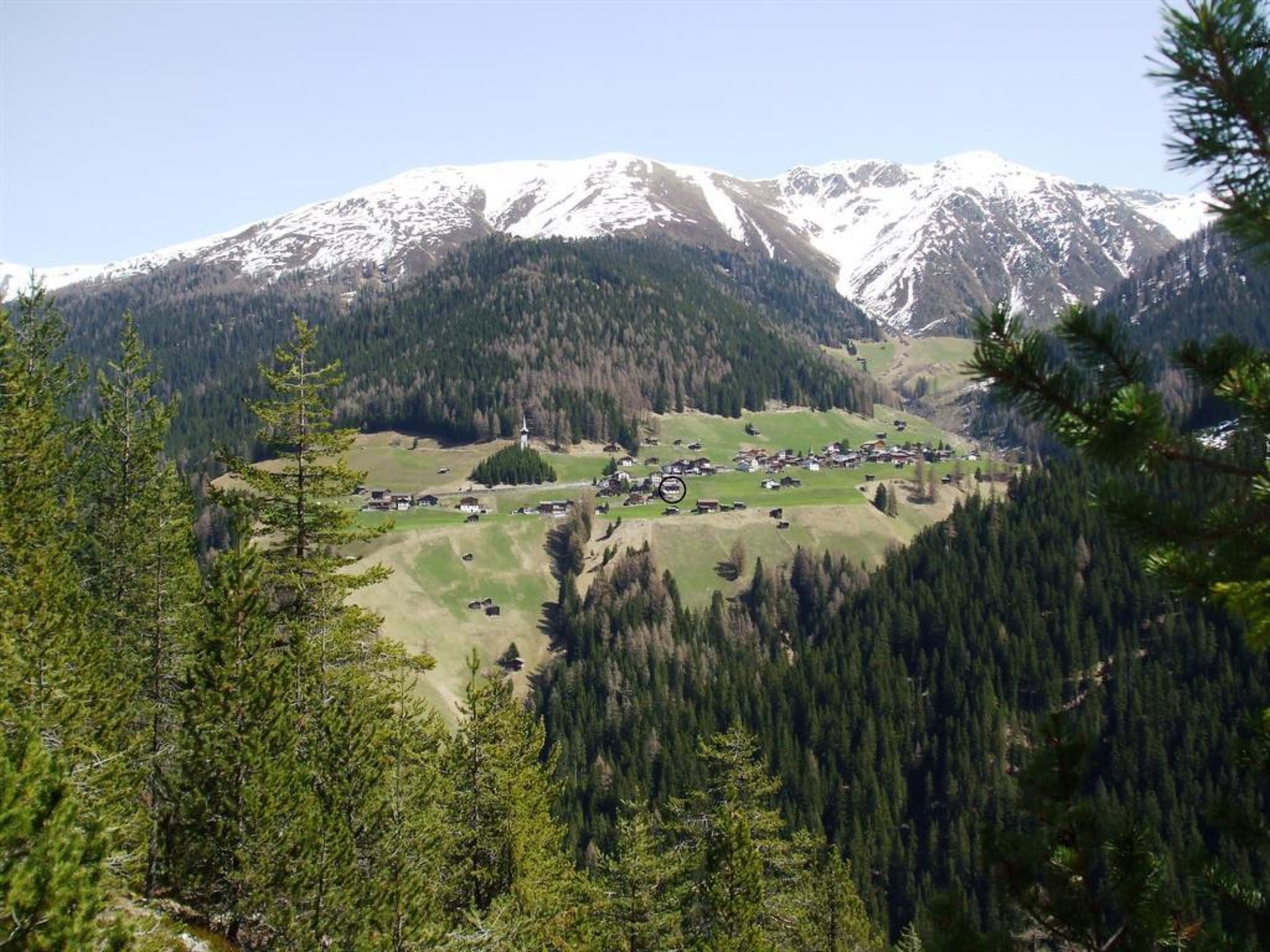Paisagem montanhosa com uma pequena aldeia, casas e uma igreja.