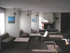 Ein Zimmer mit Kamin, einer Couch, einem Sessel und einem Tisch.