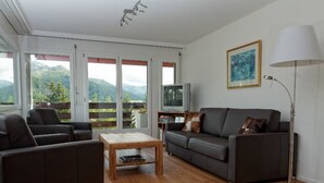 A living room with a sofa, armchair, coffee table, TV, and a lamp. - Friedberg 18 Appartement/Fewo, Dusche oder Bad, WC 3½-Zimmerwohnung by Interhome (Davos)
