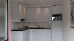 A modern kitchen with white cabinets, a black countertop, and a built-in oven. - Friedberg 18 Appartement/Fewo, Dusche oder Bad, WC 3½-Zimmerwohnung by Interhome (Davos)