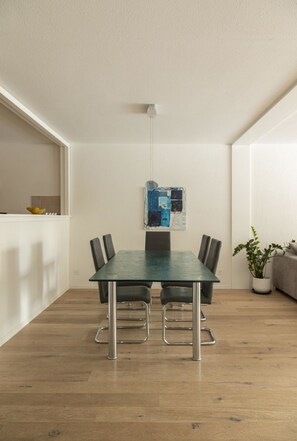 A dining area with a rectangular table, six chairs, a hanging light fixture, and a potted plant. - 2½-Zimmerwohnung by Interhome (Davos)