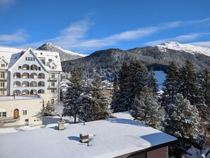 Eine verschneite Berglandschaft mit einem Gebäude, das mehrere Balkone und ein schneebedecktes Dach hat.