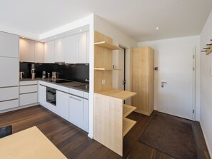 A modern kitchen with white cabinets, a black countertop, and a built-in oven. - Barbata 8 Appartement/Fewo, Dusche oder Bad, WC 1 1/2-Zimmerwohnung by Interhome (Davos)