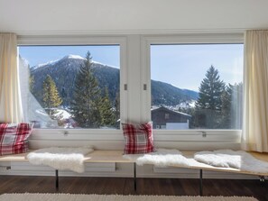 A room with a large window, a bench with plaid cushions, and a view of a snowy mountain. - Barbata 8 Appartement/Fewo, Dusche oder Bad, WC 1 1/2-Zimmerwohnung by Interhome (Davos)