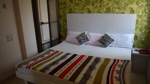 Una cama con ropa de cama a rayas, dos almohadas, una mesita de noche con un teléfono y una ventana con vistas.