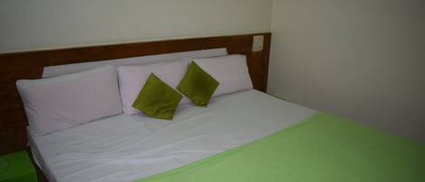 A bed with a wooden headboard, two pillows, and a green blanket.