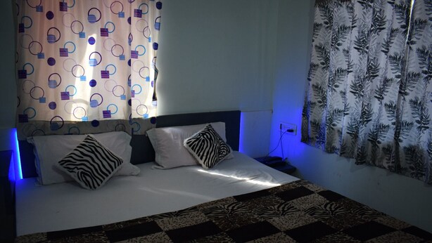 Una cama con un cojín estampado con diseño de cebra, una colcha estampada y una cortina con diseños circulares.