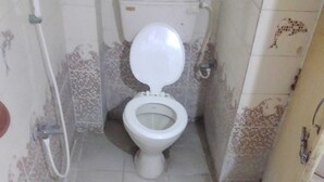 Um banheiro pequeno e estreito com vaso sanitário branco, assento rosa e paredes revestidas de azulejos.