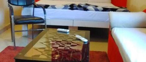 A room with a bed, a chair, a table, and a red carpet.