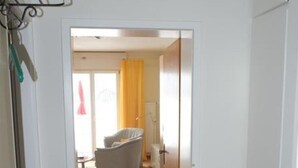 Un pasillo que da a una habitación con una silla y un tapete amarillo.