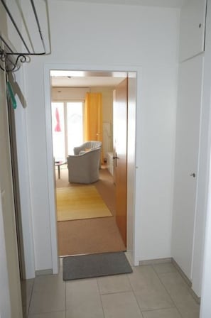 Ein Flur, der zu einem Raum mit einem Sessel und einem gelben Teppich führt.