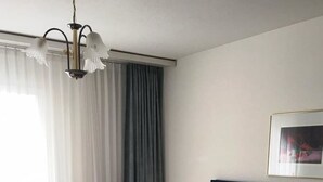 Un lit bien fait dans une chambre avec une tête de lit sombre, un luminaire suspendu et un tableau encadré au mur.