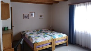 Een slaapkamer met een houten bed, een klein bureau en een raam met gordijnen.