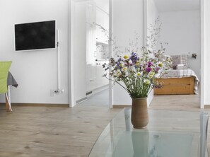 Ein modernes Zimmer mit einem Glastisch, einem Holzschrank und einem Bett mit kariertem Überwurf.