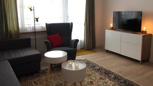 Una sala de estar con sofá, sillón, televisor y una mesita con velas.