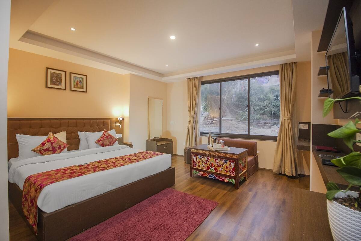 Una habitación de hotel con una cama grande, un escritorio, una silla, un televisor y una ventana con cortinas.