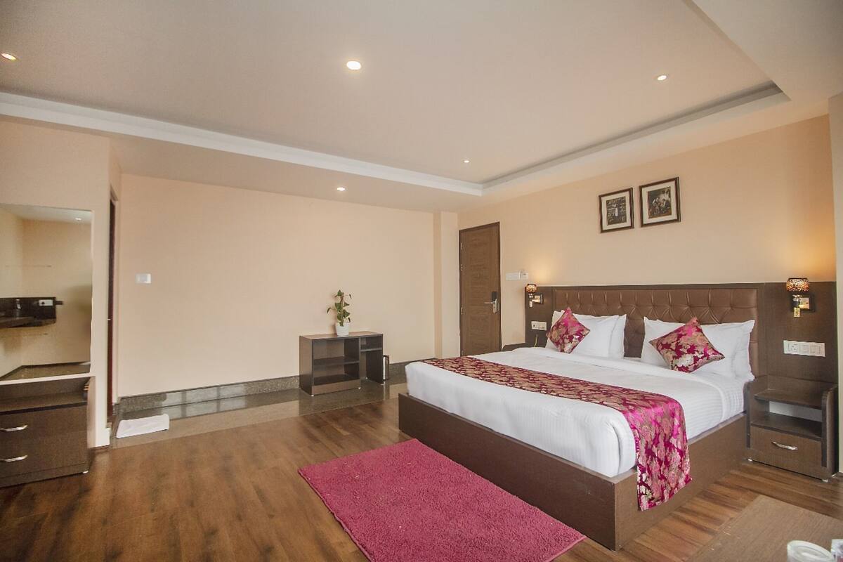 Una habitación de hotel con una cama grande, una mesita de noche, un espejo y una puerta.