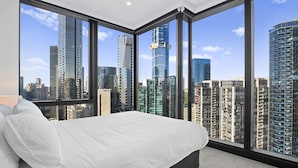 A modern bedroom with a large bed, a view of a cityscape through floor-to-ceiling windows, and a minimalist design. - Bright Apt Southbank Near Crown Casino ,pool &gym (Melbourne)