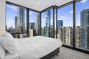 A modern bedroom with a large bed, a view of a cityscape through floor-to-ceiling windows, and a minimalist design. - Bright Apt Southbank Near Crown Casino ,pool &gym (Melbourne)