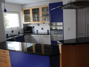 Eine moderne Küche mit schwarzem Arbeitsplatz, Edelstahlgeräten und blauen Schränken.