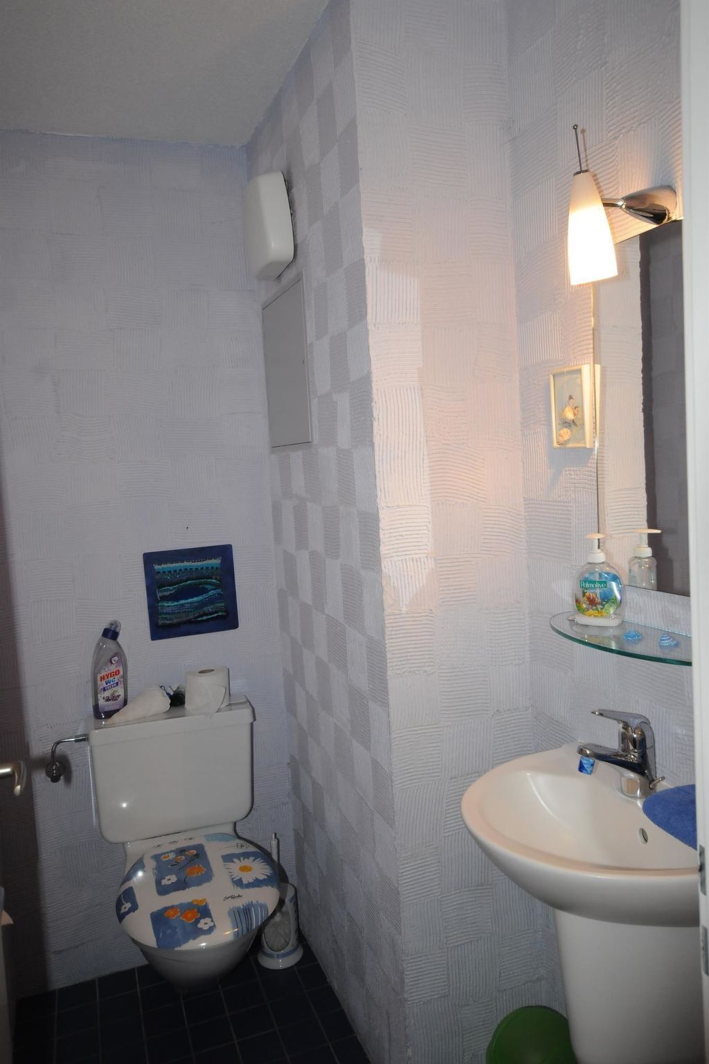 Un baño con inodoro, lavamanos y espejo.